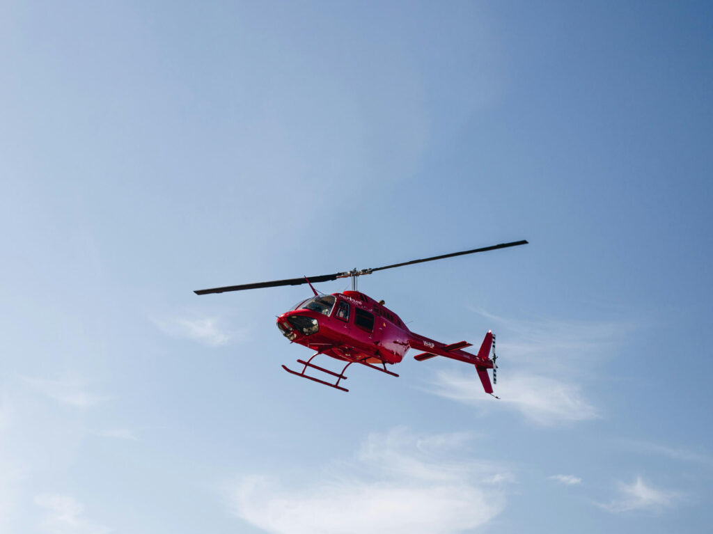 Roter Rettungshelikopter im Flug vor blauem Himmel